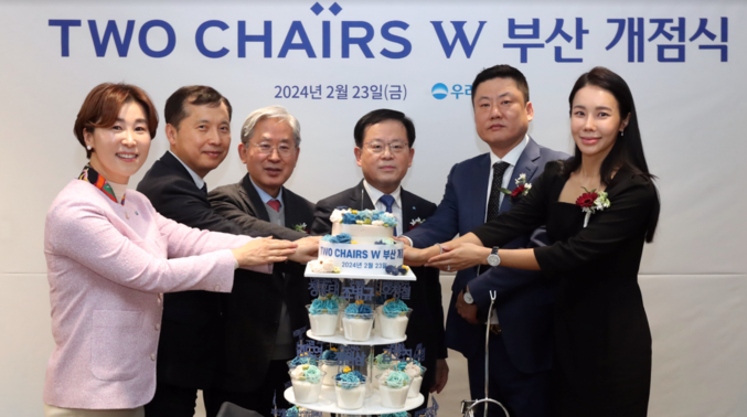 우리은행은 지난 2월 23일 ‘투체어스 W(Two Chairs W) 부산’ 개점식을 가진 가운데 (좌측부터) 우리은행 박은주 지점장, KNN 김호진 전무, 인당의료재단 정흥태 이사장, 우리은행 조병규 은행장, 금양상선 우정철 부사장, 우리은행 김도연 고객이 투체어스 W 부산 개점을 기념해 케이크 커팅식을 하고 있다. 사진 | 우리은행