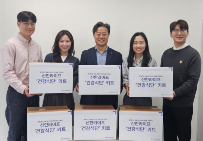 김순기(가운데) 신한라이프빛나는재단 사무국장과 신한라이프 임직원들이 결식 우려 아동 대상으로 지원하는 '건강식단' 키트를 들고 기념촬영을 하고 있다. 사진 | 신한라이프빛나는재단