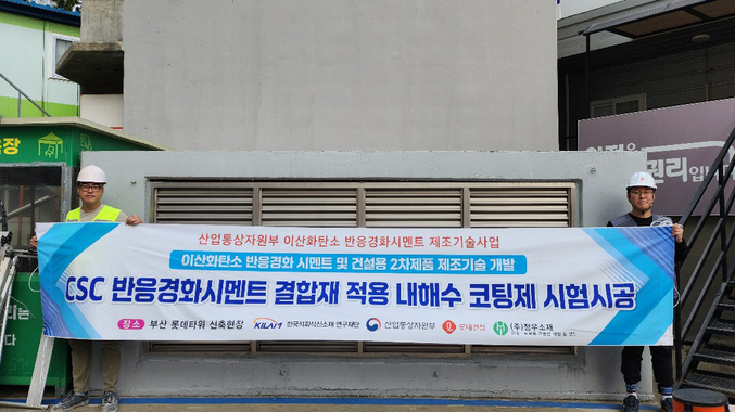 롯데건설 직원들이 부산 롯데타워 현장에서 이산화탄소 반응경화 시멘트를 활용한 코팅제를 시공하고 기념촬영을 하고 있다. 사진 | 롯데건설
