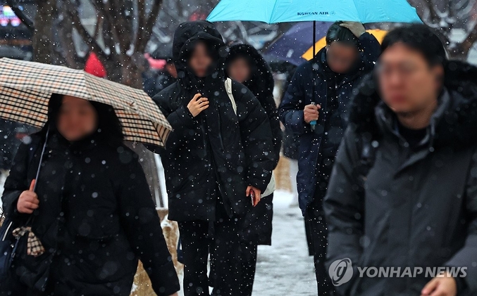 12일 새벽부터 서울에 눈이 내렸다. 종로구 세종로 사거리 일대에서 시민들이 출근하고 있다. 기상청은 기온이 오르는 오후에는 눈이 비로 바뀌는 곳이 있겠다고 예보했다. 사진 ㅣ 연합뉴스