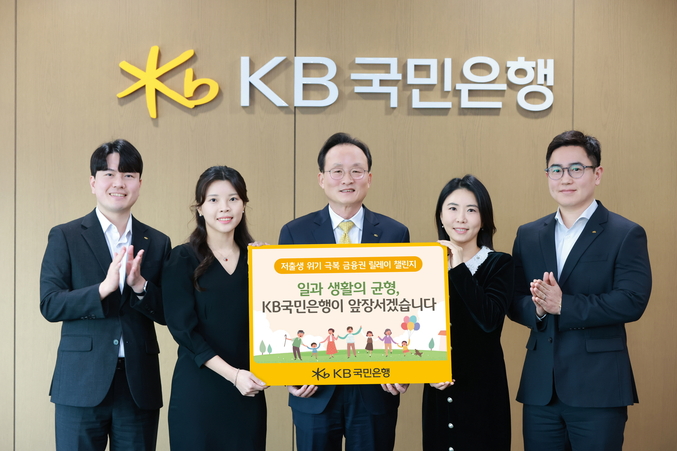 <strong>서울시 영등포구에 위치한 KB국민은행 신관에서 이환주 KB국민은행장(가운데)과 ‘KB아이사랑적금’를 기획한 KB국민은행 수신상품부 직원들이 '저출생 위기 극복 챌린지'에 참여해 기념 촬영을 하고 있다. 사진 | KB국민은행</strong>