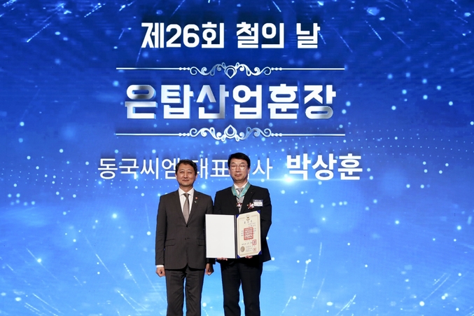 제 26회 철의 날 은탑산업훈장을 수훈한 박상훈 동국씨엠 대표이사 사장(오른쪽)이 안덕근 산업부장관(왼쪽)과 기념사진을 찍는 모습. 사진 | 동국제강