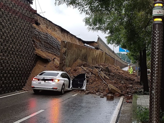 16일 집중 호우로 경기 오산 가장교차로 고가도로 옹벽이 붕괴돼 차량 2대가 깔리는 사고가 발생했다. 사진 ㅣ 연합뉴스(경기도소방재난본부 제공)
